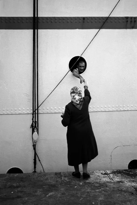 A woman in front of a wall, holding a round mirror.